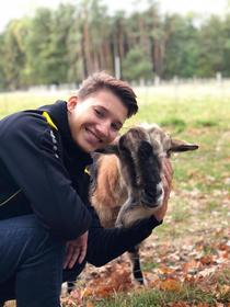 junge Frau mit einer Ziege auf der Wiese